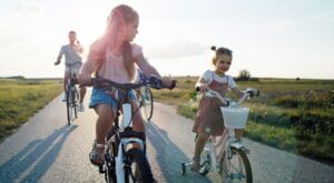 girls riding bicycles on a trail followed by their dad, enjoying the East Orlando allure